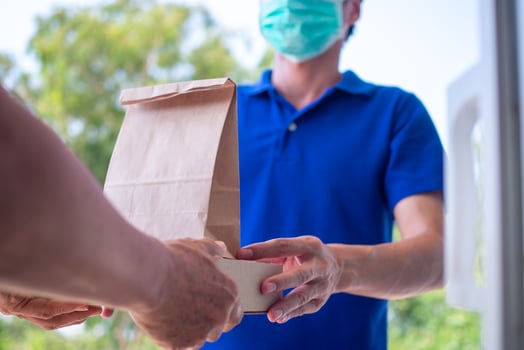 One woman ordered food online to eat at home. The person  orders products or food online, receives parcels from delivery man That put a mask on the door of the house. photo