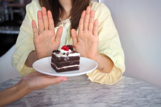 A woman in health care uses a hand to push a chocolate cake. Refused to eat foods that contain trans fats photo