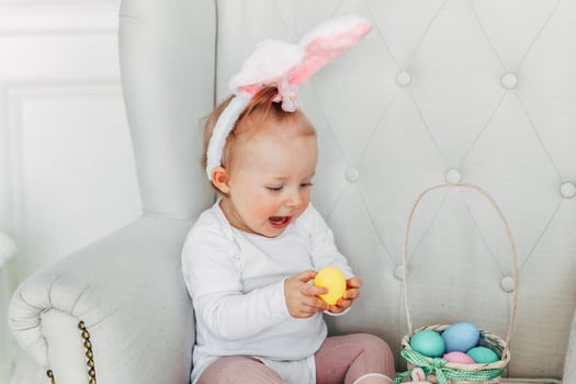 Little child girl wearing bunny ears on Easter day and playing with painted eggs photo