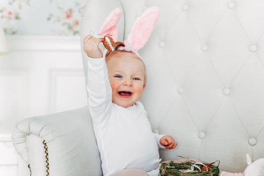 Little child girl wearing bunny ears on Easter day and playing with painted eggs photo
