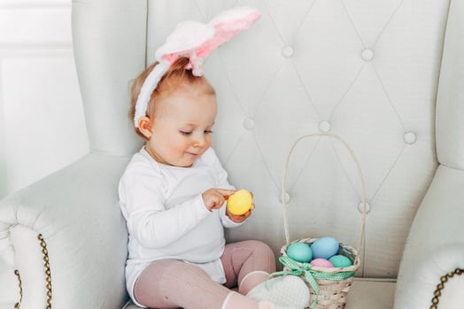 Little child girl wearing bunny ears on Easter day and playing with painted eggs photo