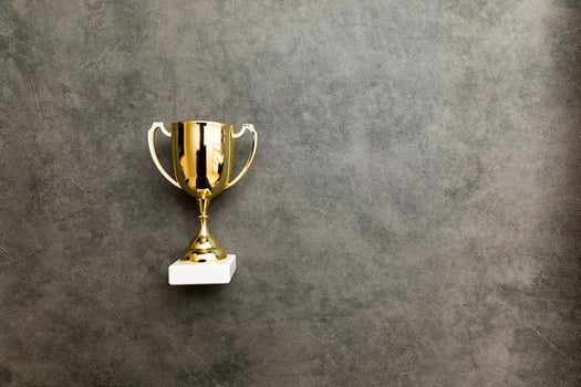 Simply flat lay design winner or champion gold trophy cup on concrete stone grey background. Victory first place of competition. Winning or success concept. Top view copy space. photo