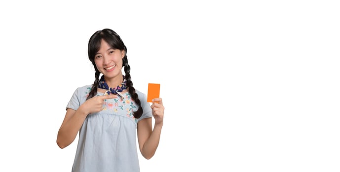 Portrait of beautiful happy young asian woman in denim dress holding credit card on white background photo