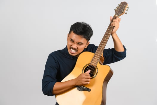 Portrait of Young Asian man playing an acoustic guitar isolated on white background photo