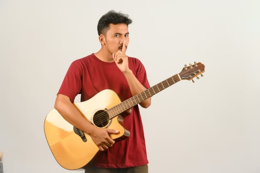 Portrait of Young Asian man in red t-shirt with an acoustic guitar isolated on white background photo