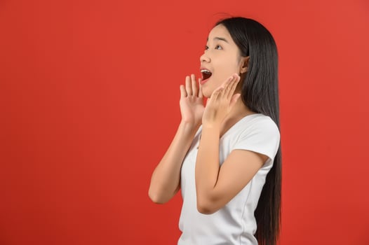 Portrait of Young asian woman in white t-shirt looking up and exciting isolated on red background photo
