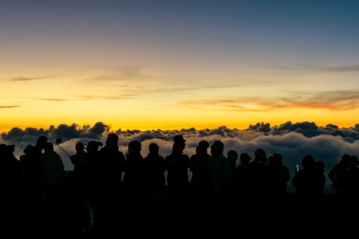 Silhouette person group watching floating sea of clouds,Sea of fog, Sky above clouds,taking cloudscape photos with mobile phones in the morning,sun rising,travel long weekend,Inthanon mountain.