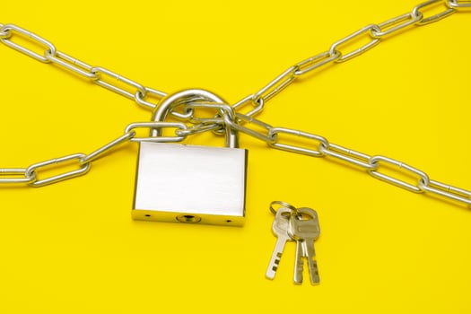lock on a chain on a yellow background, a bunch of keys lies nearby photo