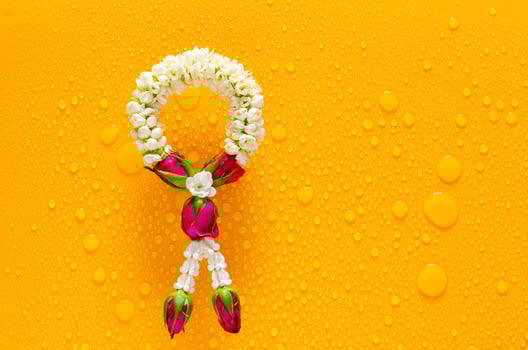 Jasmine garland puts on clear mirror that have wet yellow background below for Songkran festival concept. photo