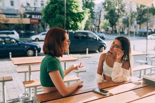 Two pretty girlfriends talking while sitting in a bar outdoors photo