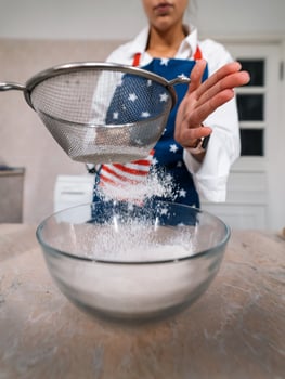 Woman sifting flour through sieve. Selective focus. photo