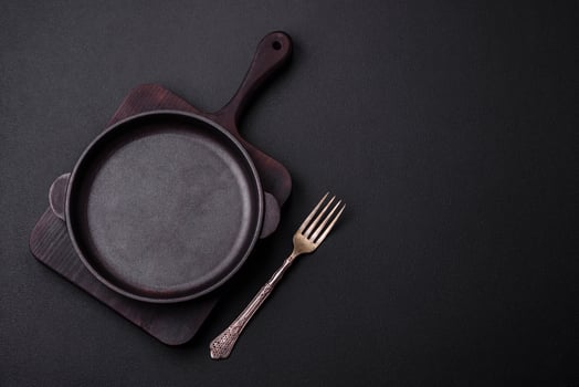 Empty round cast iron skillet on dark textured concrete background photo