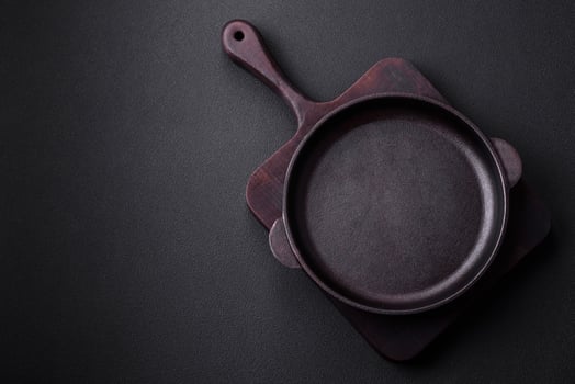Empty round cast iron skillet on dark textured concrete background photo