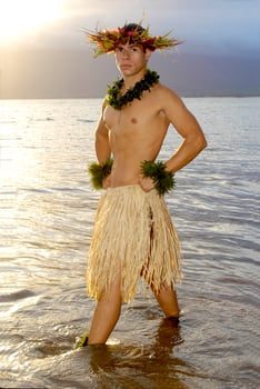 Handsome male hula dancer stands in the water as the sun sets. photo
