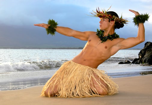 This very handsome male hula dancer is posed in a traditional position on the sand right on the wet sand next to the ocean. photo