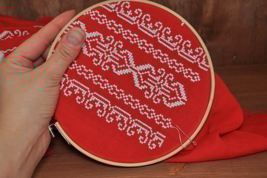 Hand embroidery cross on red cloth with white thread photo