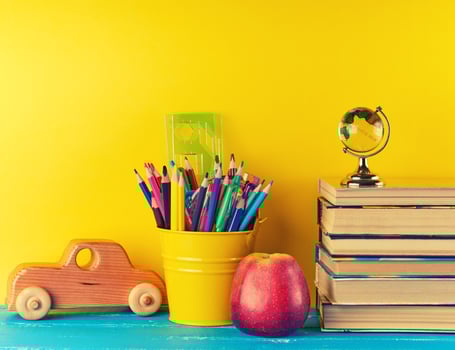 background back to school with children's stationery pencils, books, apple, glass globe photo