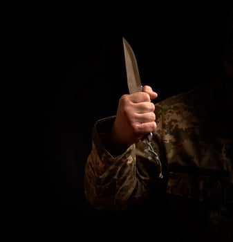 male hand holds steel sharp knife, low key photo