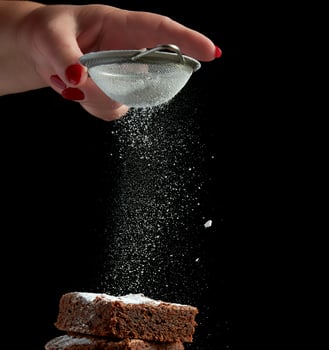 square baked brownie chocolate cake slices sprinkled with white sugar from an iron sieve photo