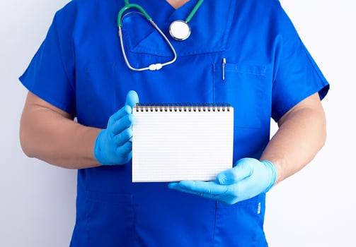 doctor in blue uniform and sterile latex gloves holding open blank notebook photo