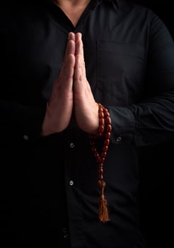adult man in a black shirt folded his arms in front of his chest in a prayer pose photo
