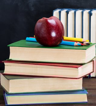 ripe red apple lying on a stack of books photo