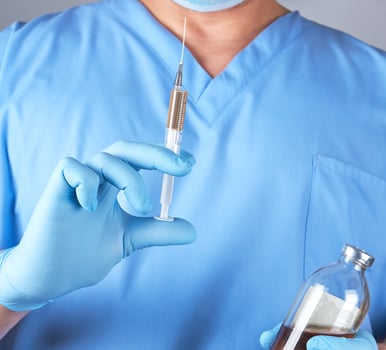 male doctor in blue uniform holding a syringe photo