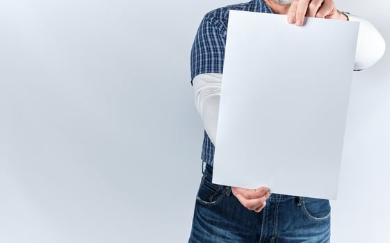man in a blue plaid shirt and jeans is holding a blank rectangular white paper sheet photo