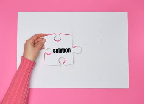 female hand holding white puzzle with the word solution, process of closing the missing element photo