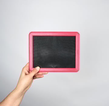hand holding an empty chalk frame on a gray background photo