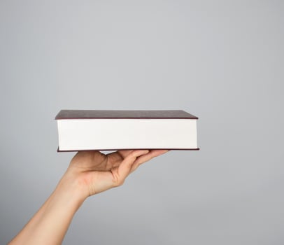 hand holds a closed book in hardcover photo
