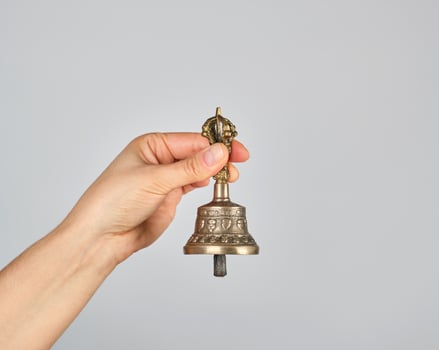 female hand holding a bronze bell for alternative medicine photo