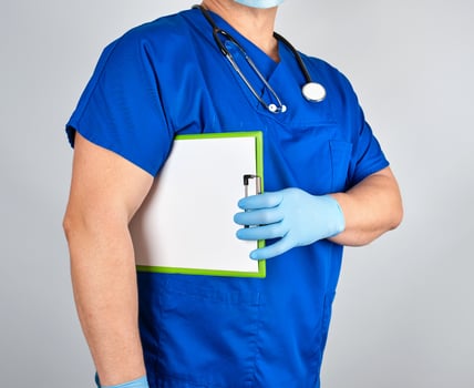 doctor in blue uniform and sterile latex gloves holds clipboard photo