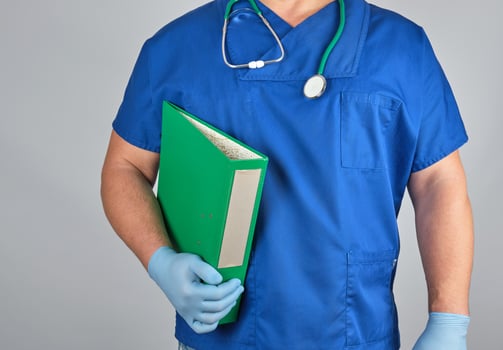 doctor in blue uniform, latex sterile gloves holds in his hand a green folder photo
