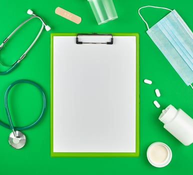 paper holder with empty white sheets, medical stethoscope, pills and textile bandage photo