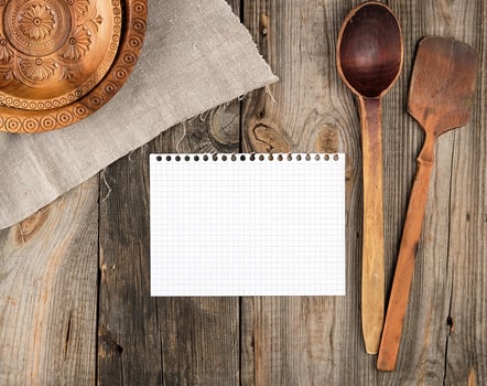 blank white paper and empty round brown carved decorative plate and wooden spoon photo