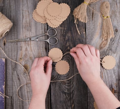 two female hands and paper tags with a brown rope on a gray wooden table photo
