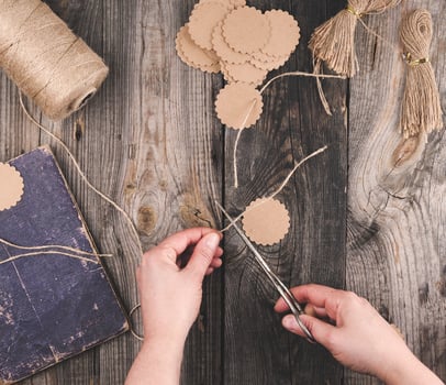 two female hands and paper tags with a brown rope on a gray wooden table photo