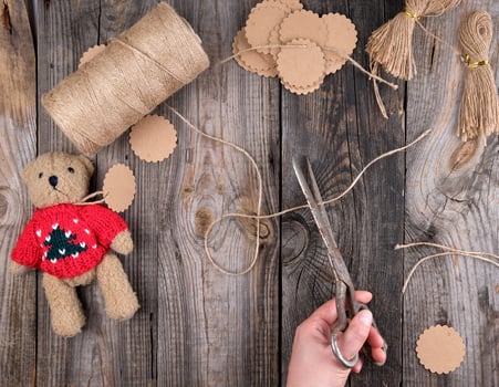 female hands cut brown rope for tags photo
