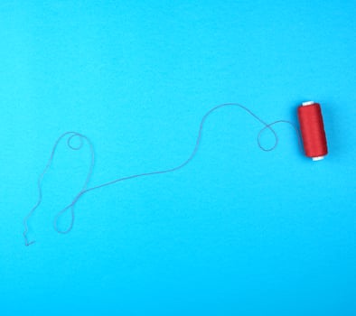 spool of red threads on a blue background photo