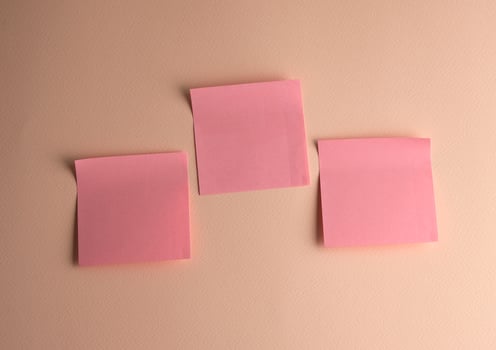 three pink paper stickers pasted on white background photo