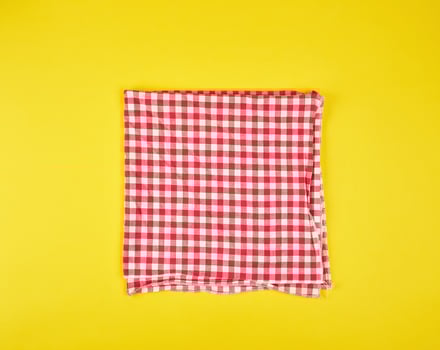folded red kitchen towel in a cage on a yellow background photo