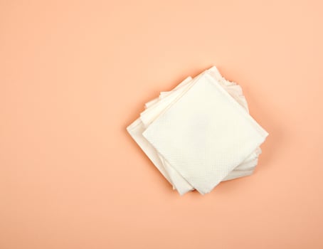 stack of white paper napkins on a beige background, top view photo