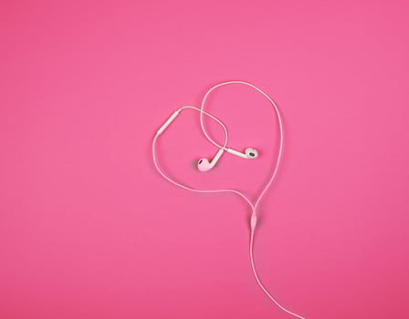 white headphones with a cable on a pink background photo