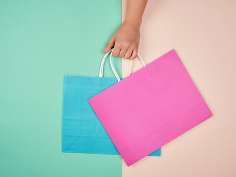 hand holding two paper shopping bags on a pastel background photo
