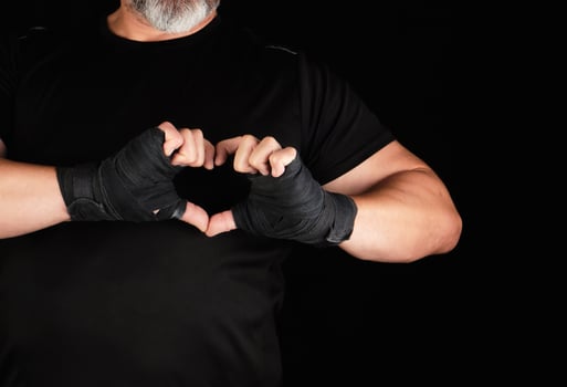 athlete shows the symbol of the heart, the palm of a man is wrapped in a black sports bandage photo