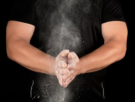 athlete in black clothes clapping, white talc magnesium fly away photo