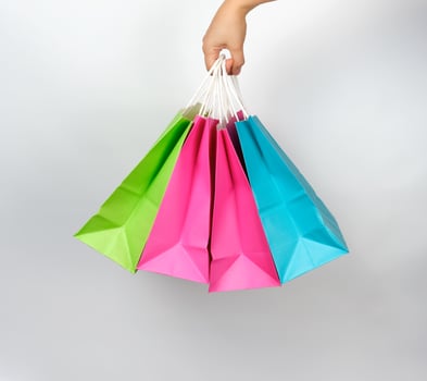 female hand holding four colored paper shopping packaging bags photo