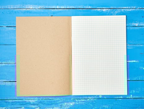 open checked school notebook on blue wooden background photo