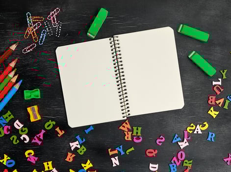 open spiral notebook with clean white sheets, wooden colored pencils photo